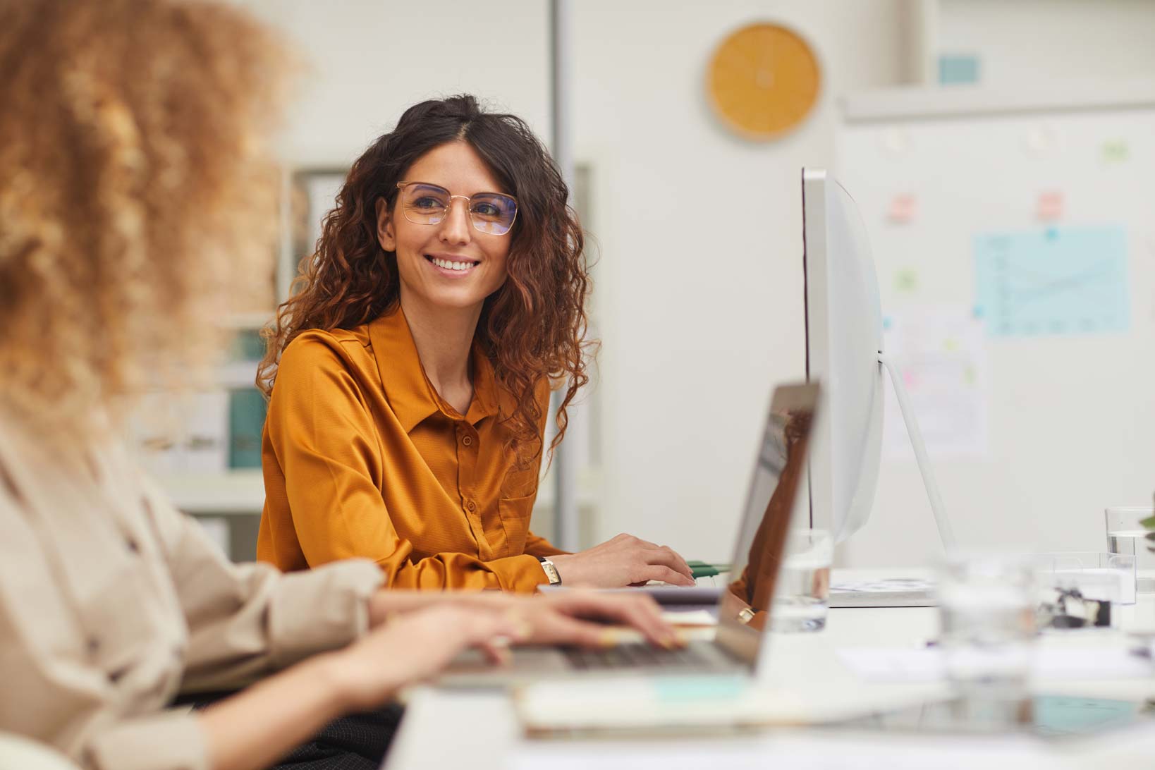 Two colleagues working at computers in a bright modern office.