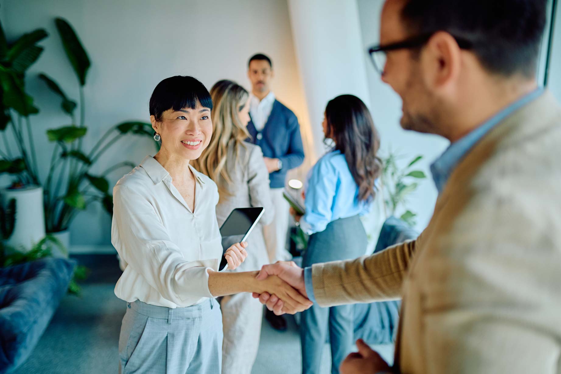 Business professionals shaking hands during a networking event in a modern office.