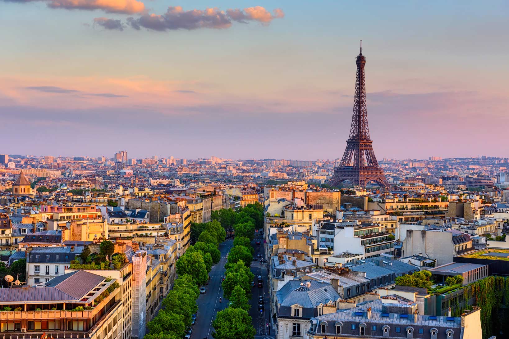 Paris skyline at sunset with the Eiffel Tower in the distance.
