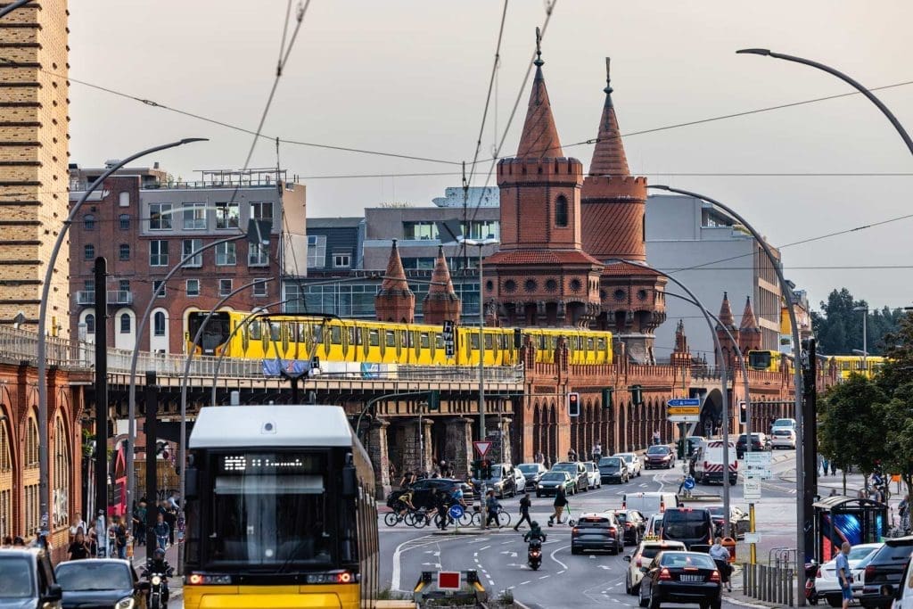 Yellow trains crossing Oberbaum Bridge in Berlin with city traffic below.