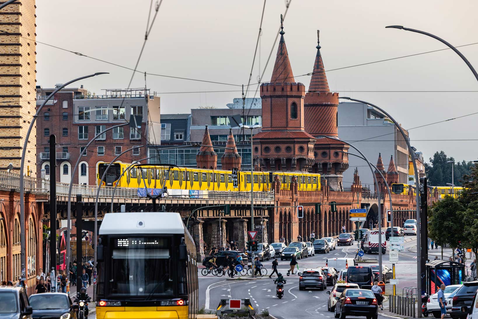 Yellow trains crossing Oberbaum Bridge in Berlin with city traffic below.