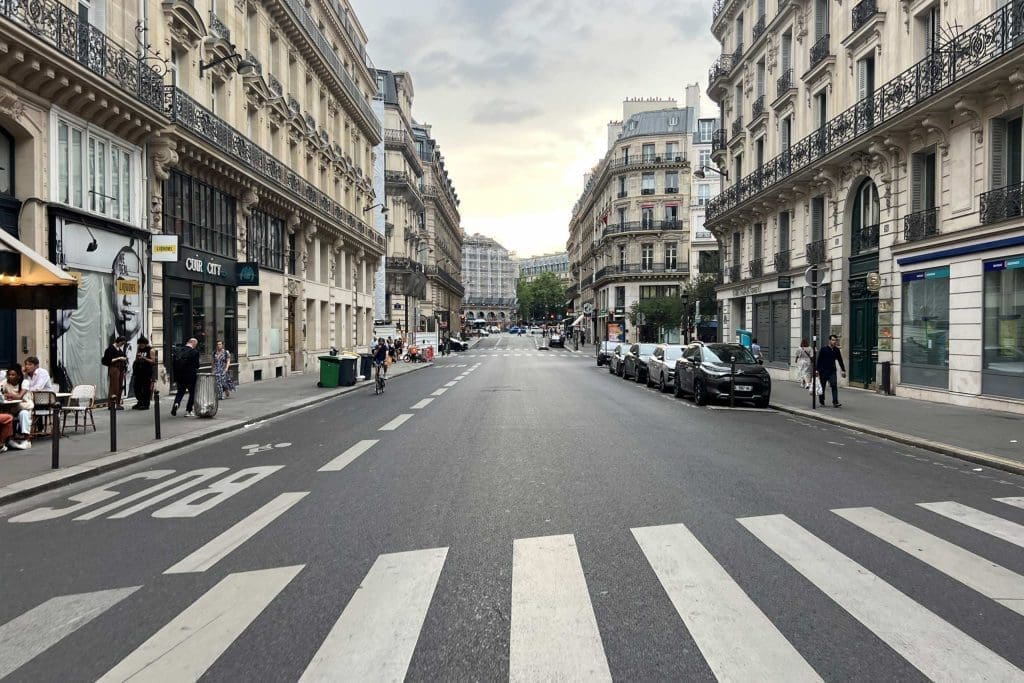 Wide pedestrian crossing on a historic European city street lined with buildings
