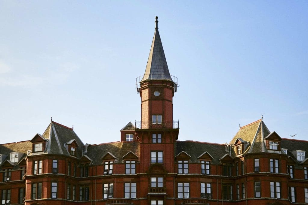 Historic red-brick building with a clock tower against a clear blue sky.