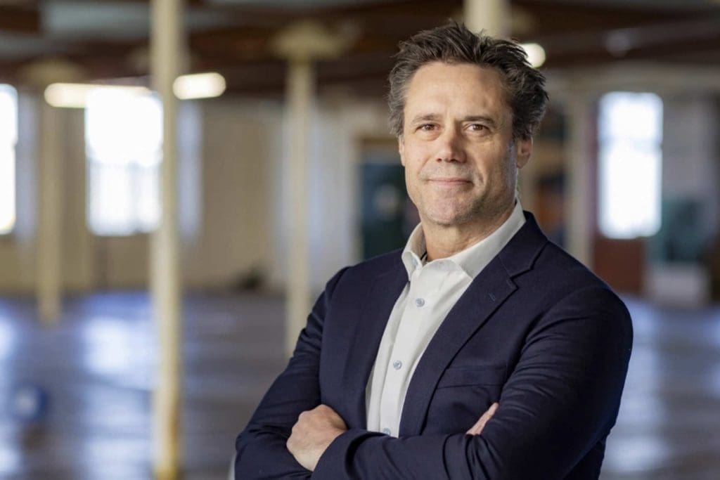 Business professional standing with arms crossed in a modern office.